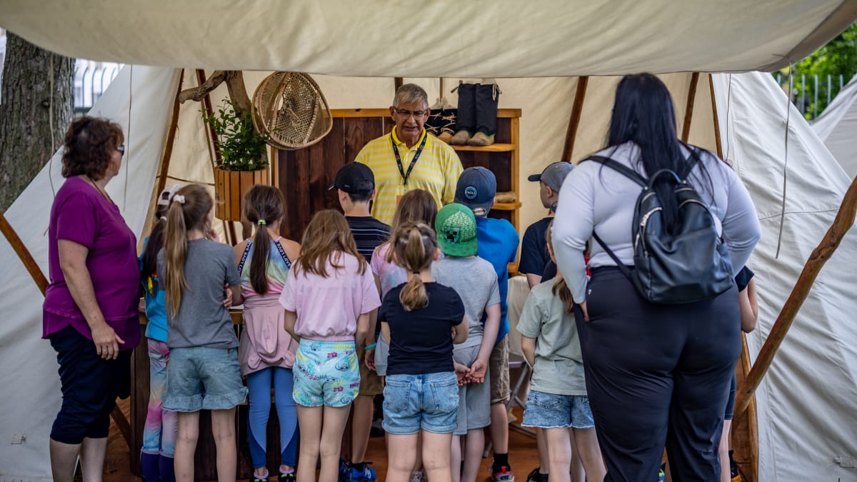 Kids and adults at a booth of Indigenous merchandise.
