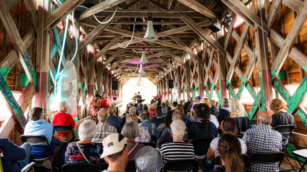 Audience seated in a barn converted into a performance venue.