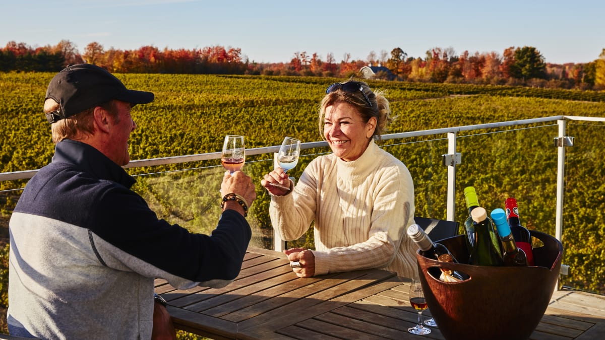Couple à l'extérieur qui déguste un verre de vin au Vignoble de l'Orpailleur en automne.