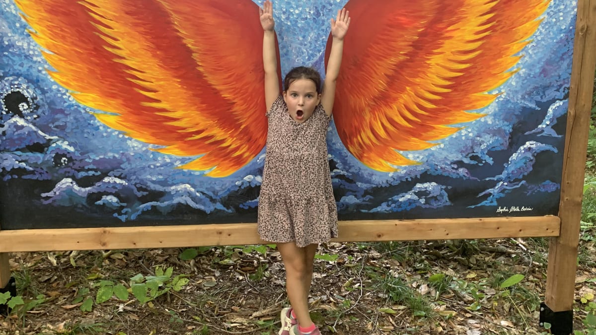 Young girl striking a pose in front of drawn wings.