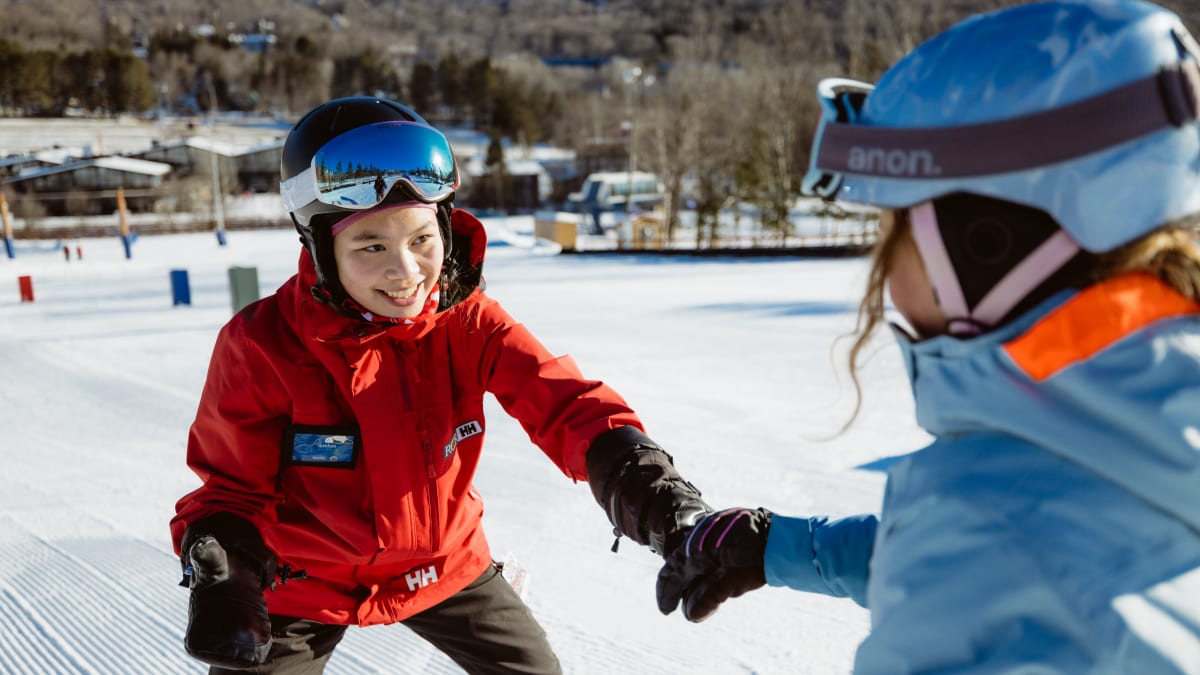 Monitrice tout sourire avec un élève sur les pistes.