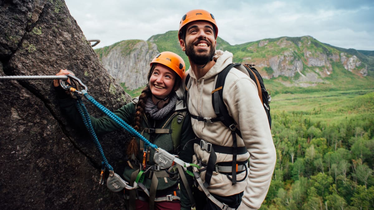Couple heureux sur la falaise d'un parcours de via ferrata au Saguenay-Lac-Saint-Jean.