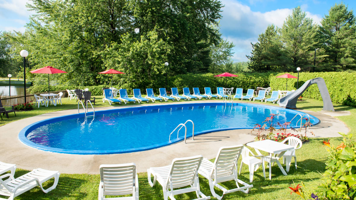 Outdoor in-ground pool surrounded by sun loungers.