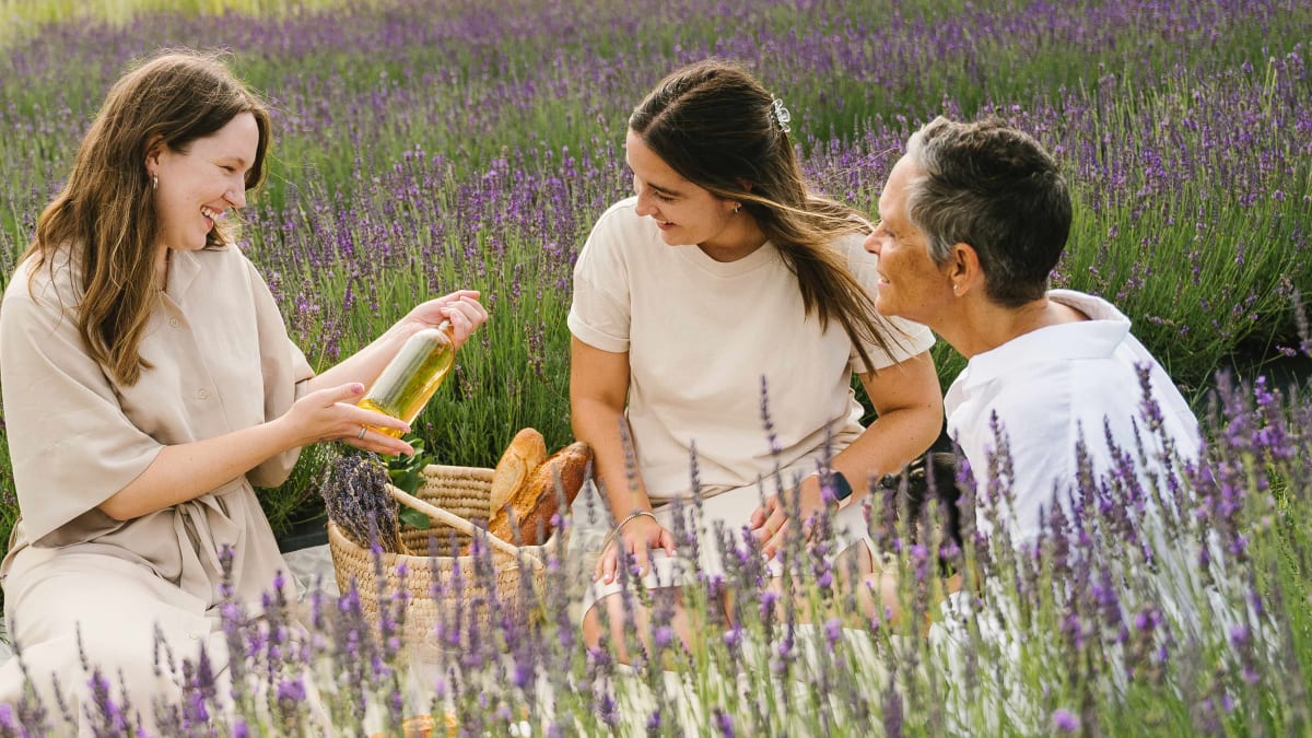 Quatre femmes souriantes en train de pique-niquer dans les champs de lavande.