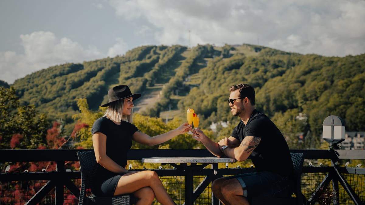 Couple sharing a drink in front of the ski hill in late summer.