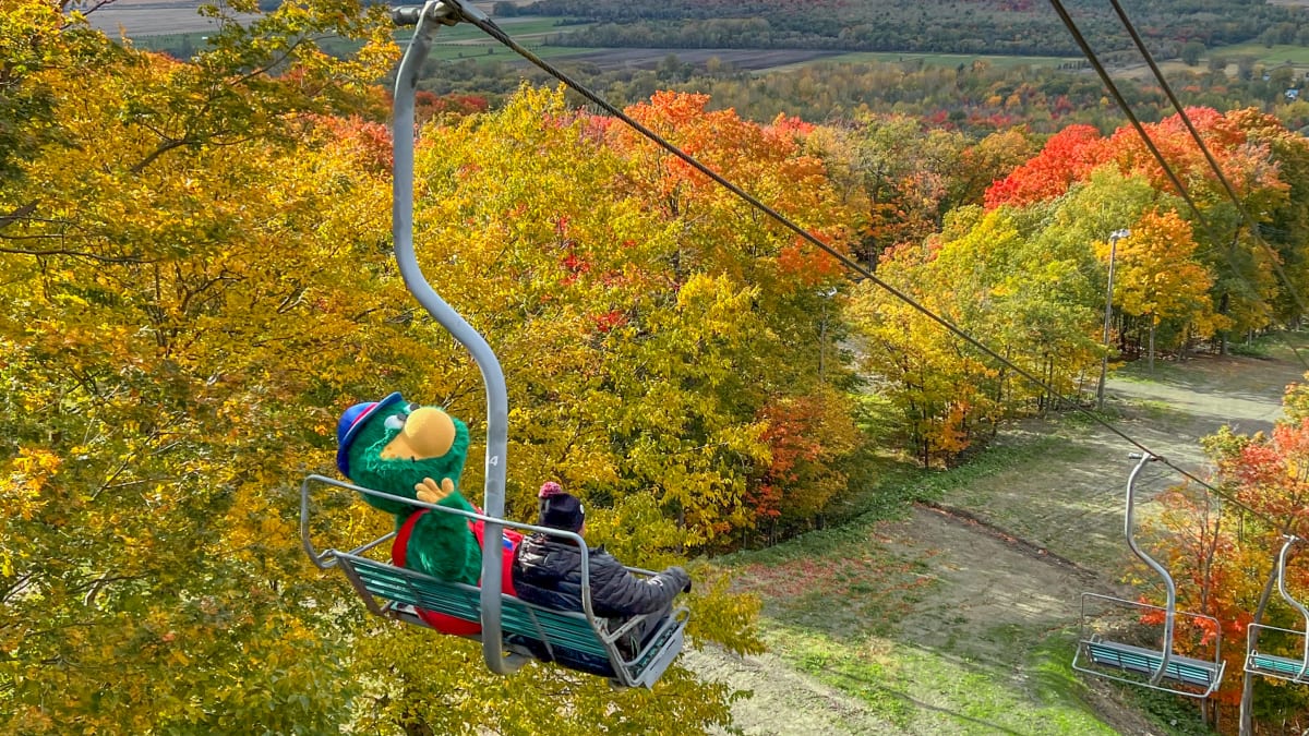 Mascotte et garçon sur un remonte-pente en automne.