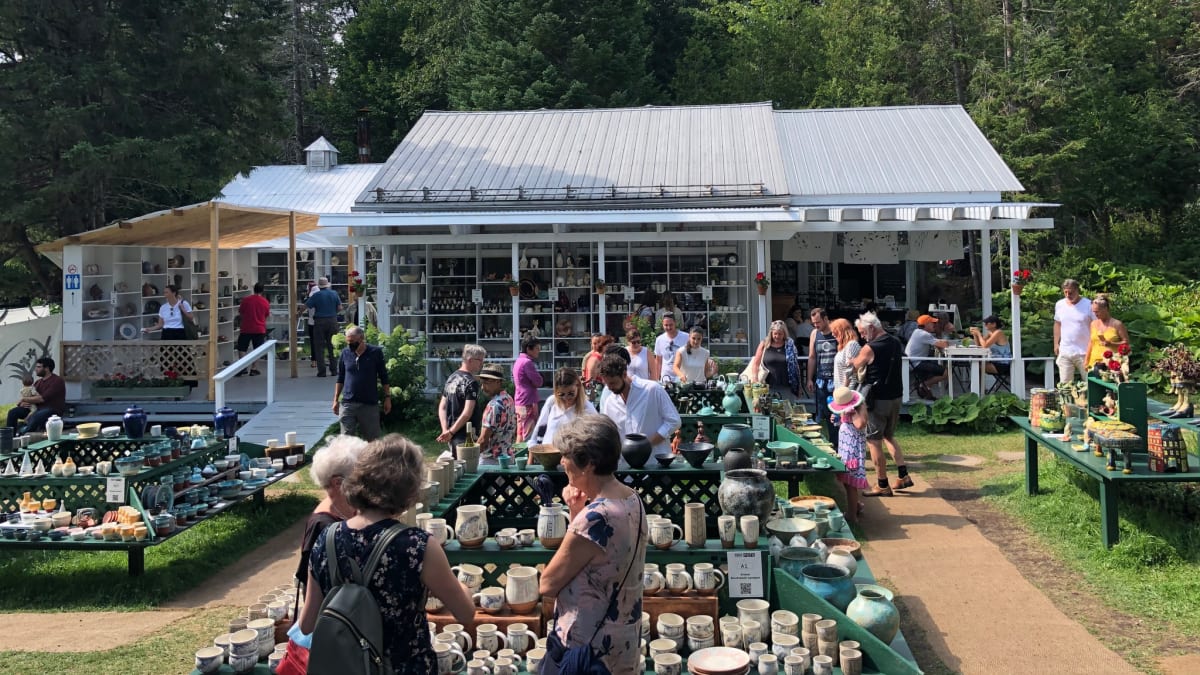 The exhibition site, with a small house and outdoor tables filled with ceramics.
