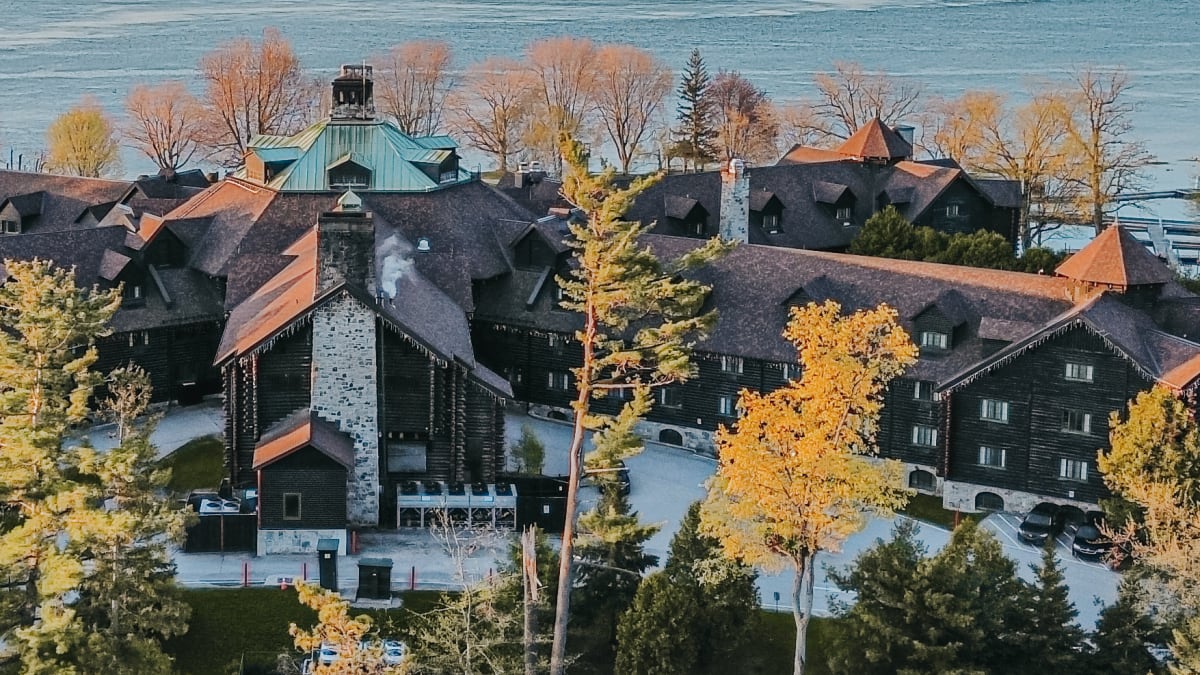 Devanture de l’hôtel en bois rond; l’entrée est entourée d’un aménagement paysager aux accents vert tendre.