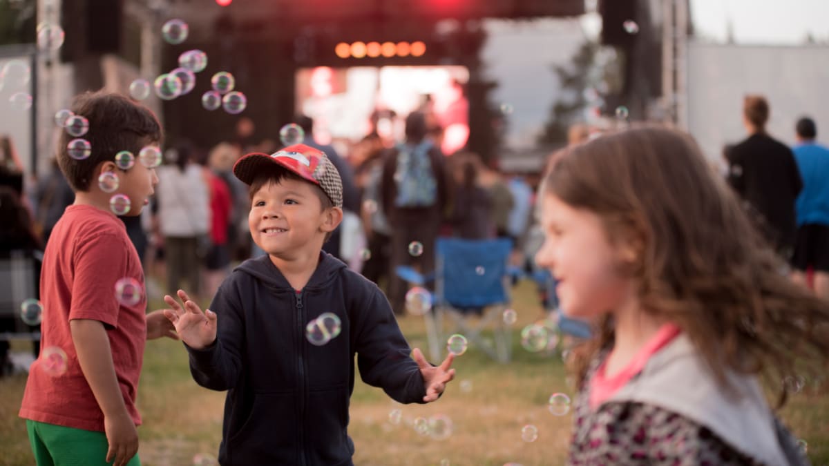 3 kids having fun in front of a stage at the festival.