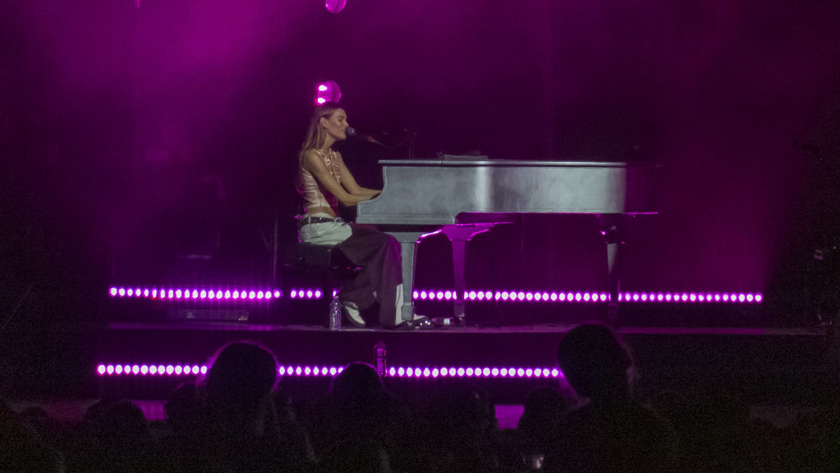 Charlotte Cardin at the piano on stage in the evening.