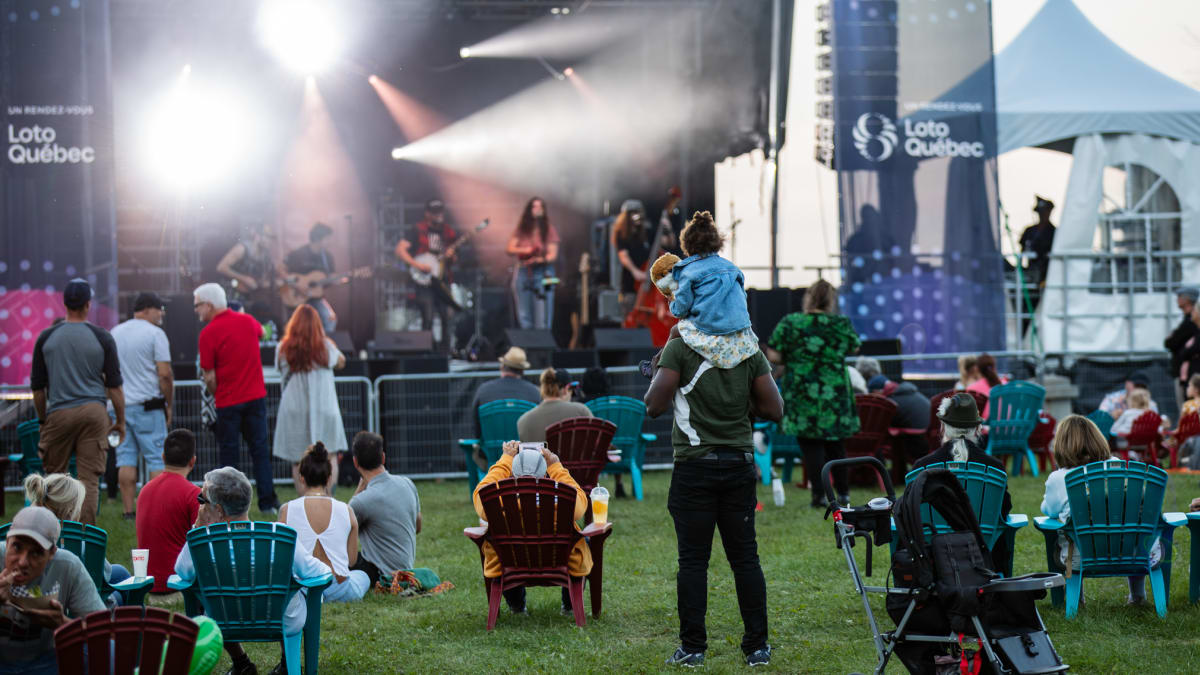 Festival grounds in front of a stage, with chairs and families.