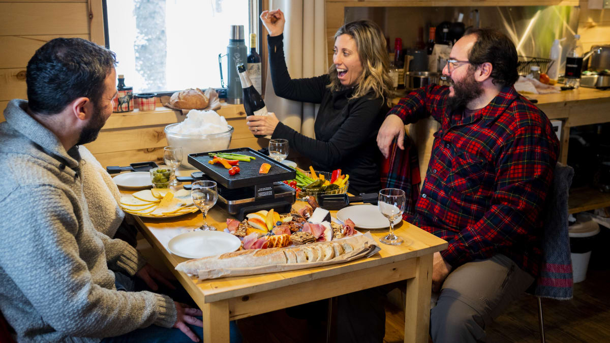 Deux couples attablés pour savourer une raclette et une bouteille de vin