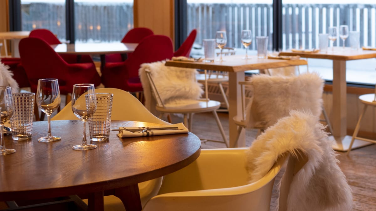 Inside of a cozy-looking bistro, with large windows and warm lighting