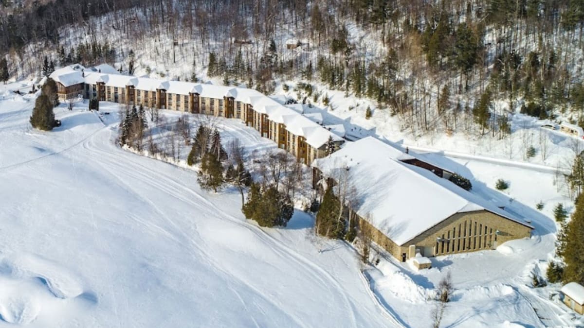 Vue aérienne de l’hôtel, entouré d’étendues enneigées et d’arbres dénués de leur feuillage.
