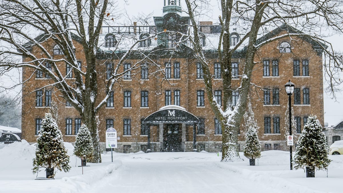 Devanture de l'Hôtel Montfort, un bâtiment d'allure historique de 4 étages, sous la neige.