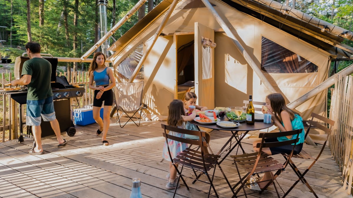 Family of four enjoying the sunshine on the terrace of their ready-to-camp tent.