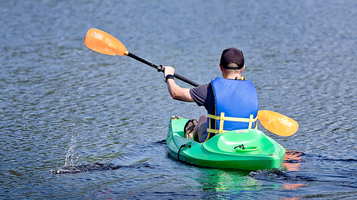 Man seen from the back kayaking on the private lake.