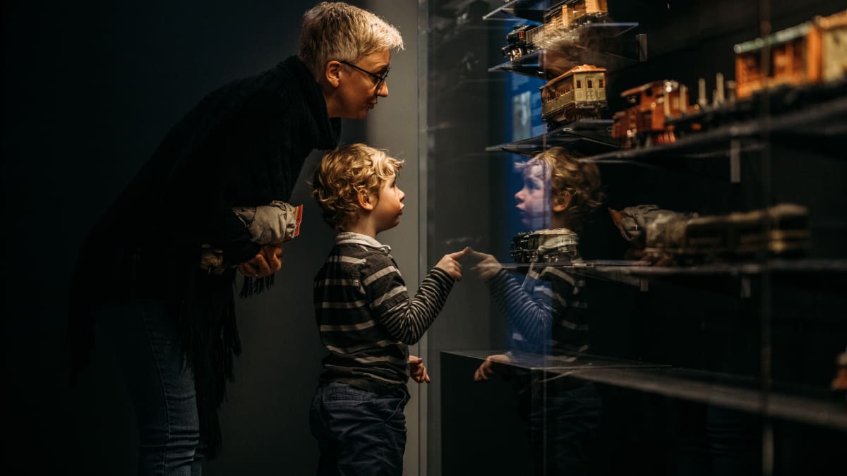 Young boy and grandparent looking at a model train exhibit