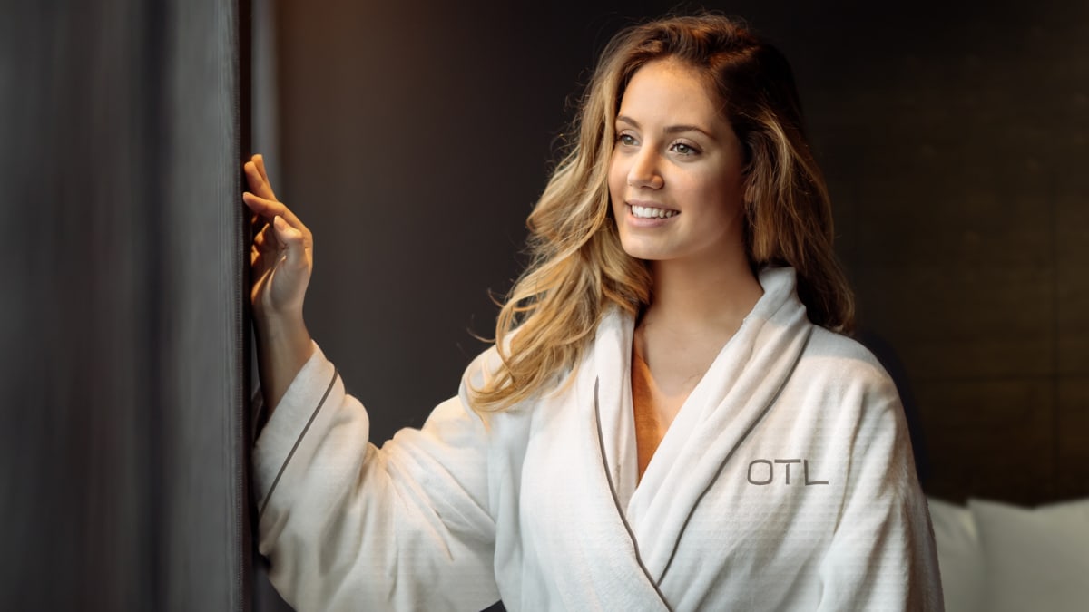 Woman in white bathrobe in a cozy-looking room.
