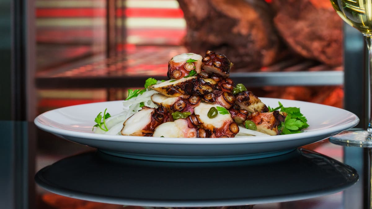 A plate of carefully prepared seafood, served with a glass of white wine.