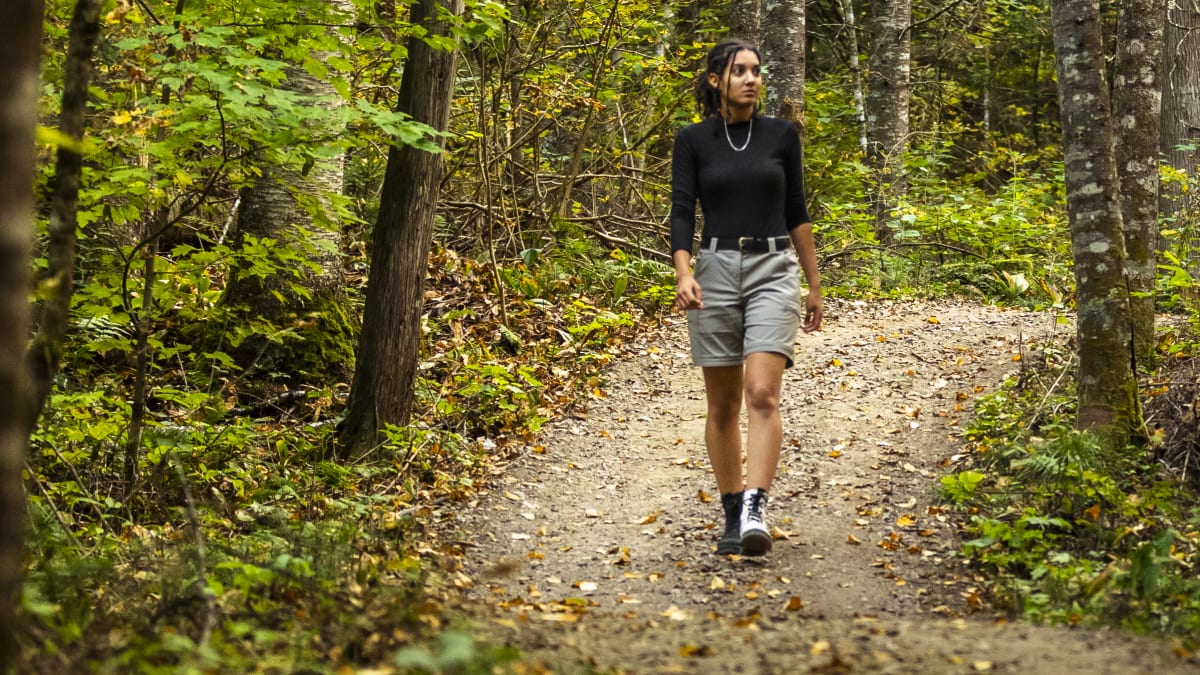 Young woman on a hiking trail in the forest in the fall
