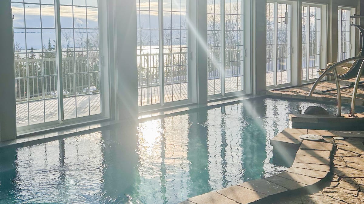 Indoor pool within a spa next to bay windows.