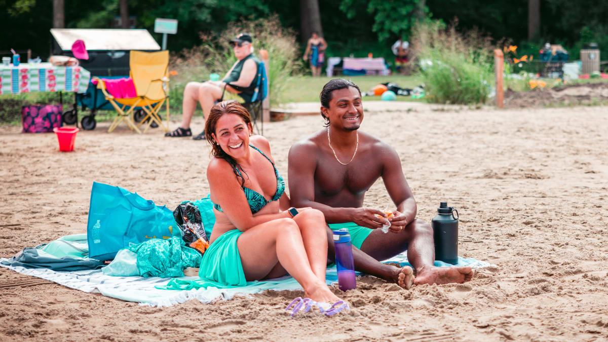 Happy-looking couple sitting on a beach towel.