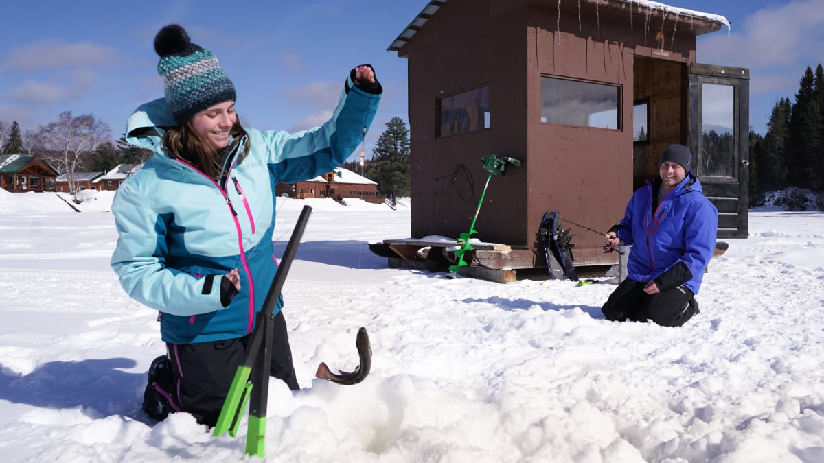Couple en train de faire de la pêche sur glace par une journée ensoleillée.