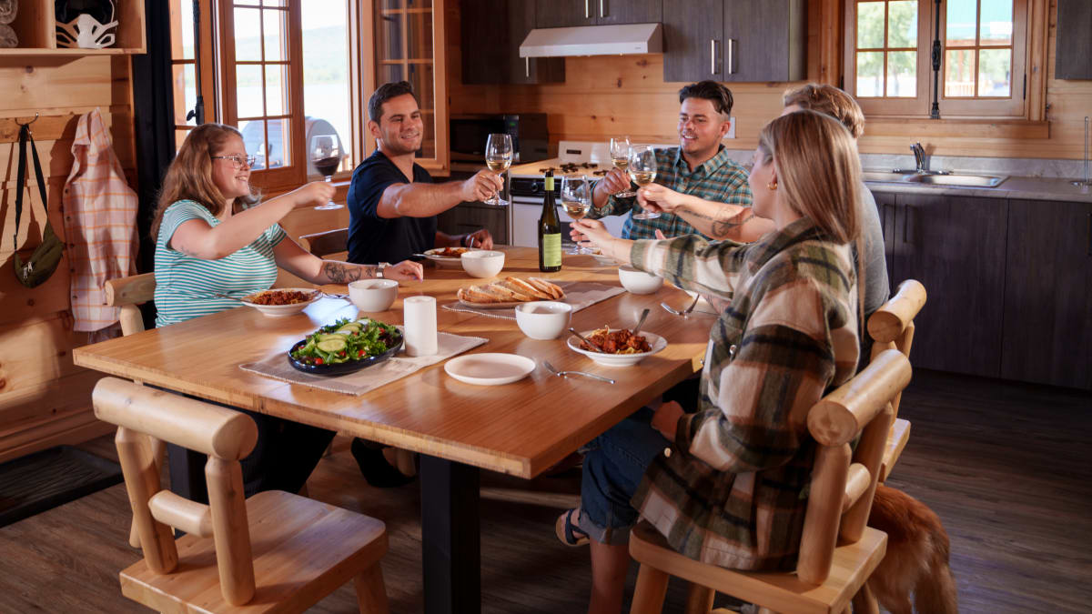 Groupe de convives autour d'une table à l'intérieur d'un chalet en bois.