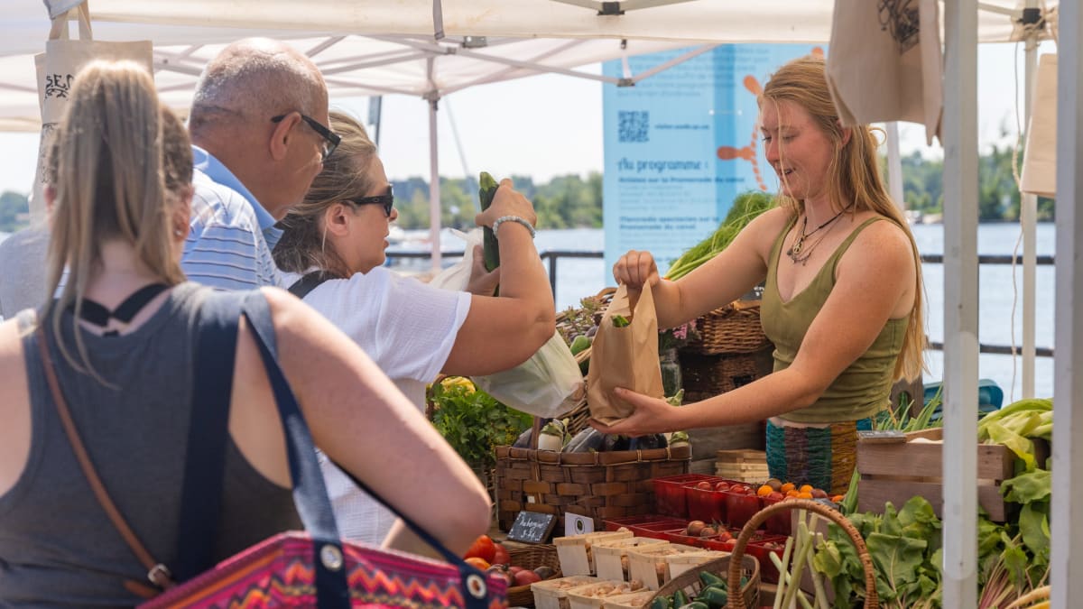 Booth at the farmer's market with customers lined up and merchant.