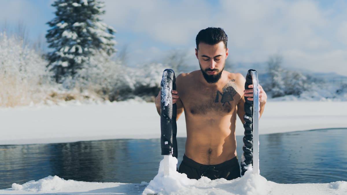 Homme qui sort d'un bassin d'eau dont les bords sont couverts de neige.