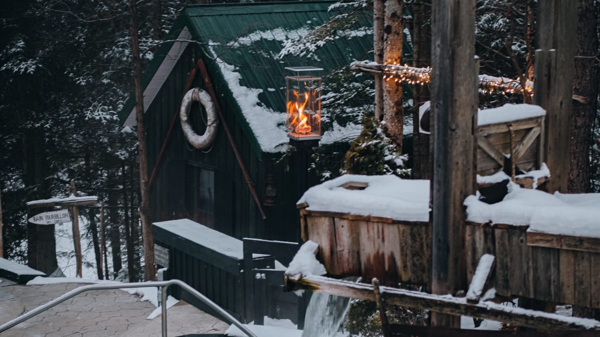 Un bain thermal entouré de neige et d’arbres à la tombée du soir.