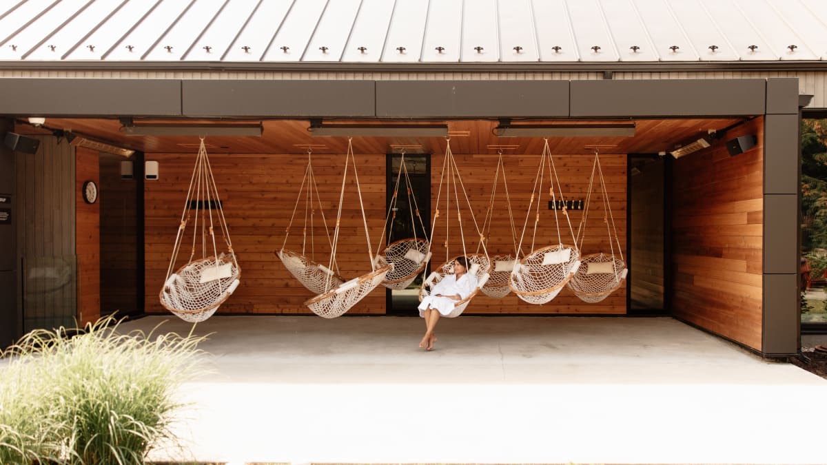 Femme dans un espace de relaxation extérieur, équipé de chaises suspendues.