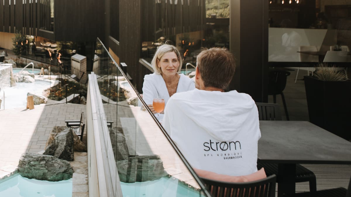 Couple installé sur la terrasse extérieure du restaurant du spa, qui donne sur les installations thermales.