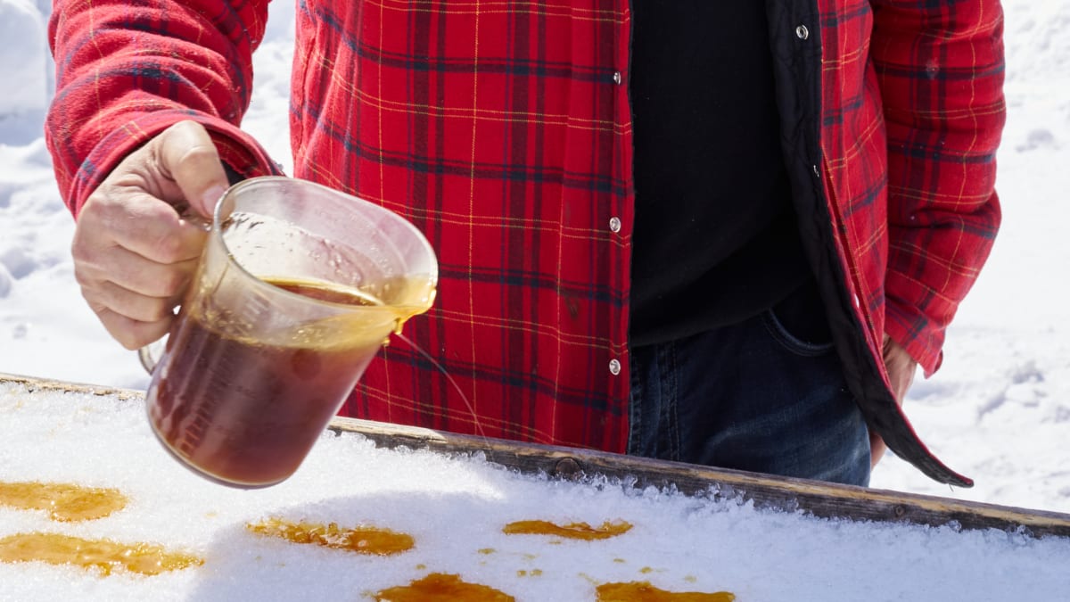 Close-up shot of a man pouring maple syrup on the snow.