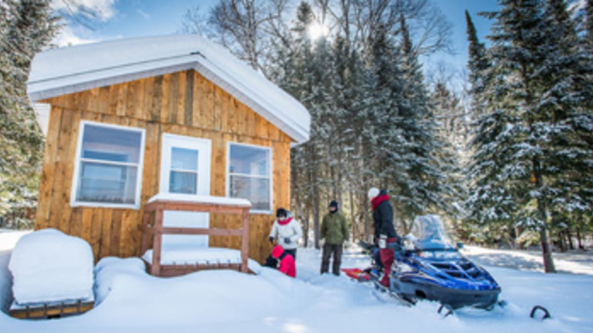 Chalet en hiver avec motoneigiste