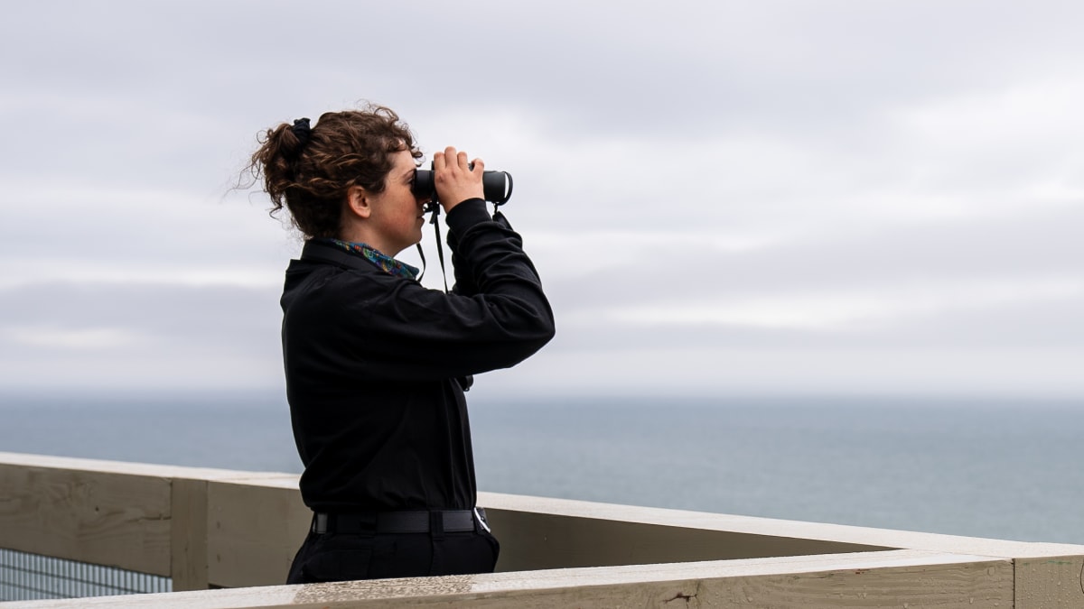 Woman looking at  the sea with binoculars.