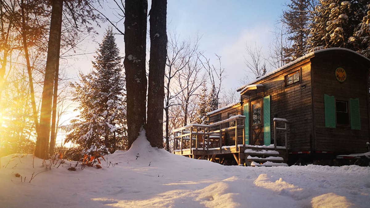 A tiny cottage in a snowy landscape under a golden natural light.