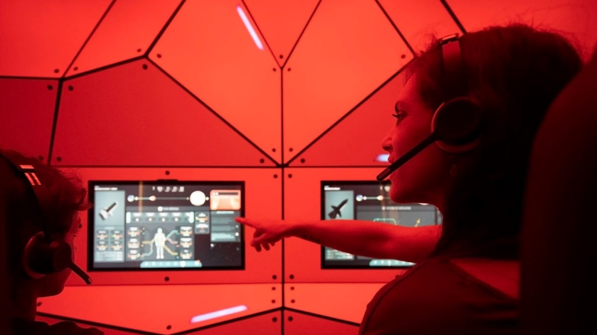 Mother and son wearing headphones sitting in front of screens at the space exhibit.