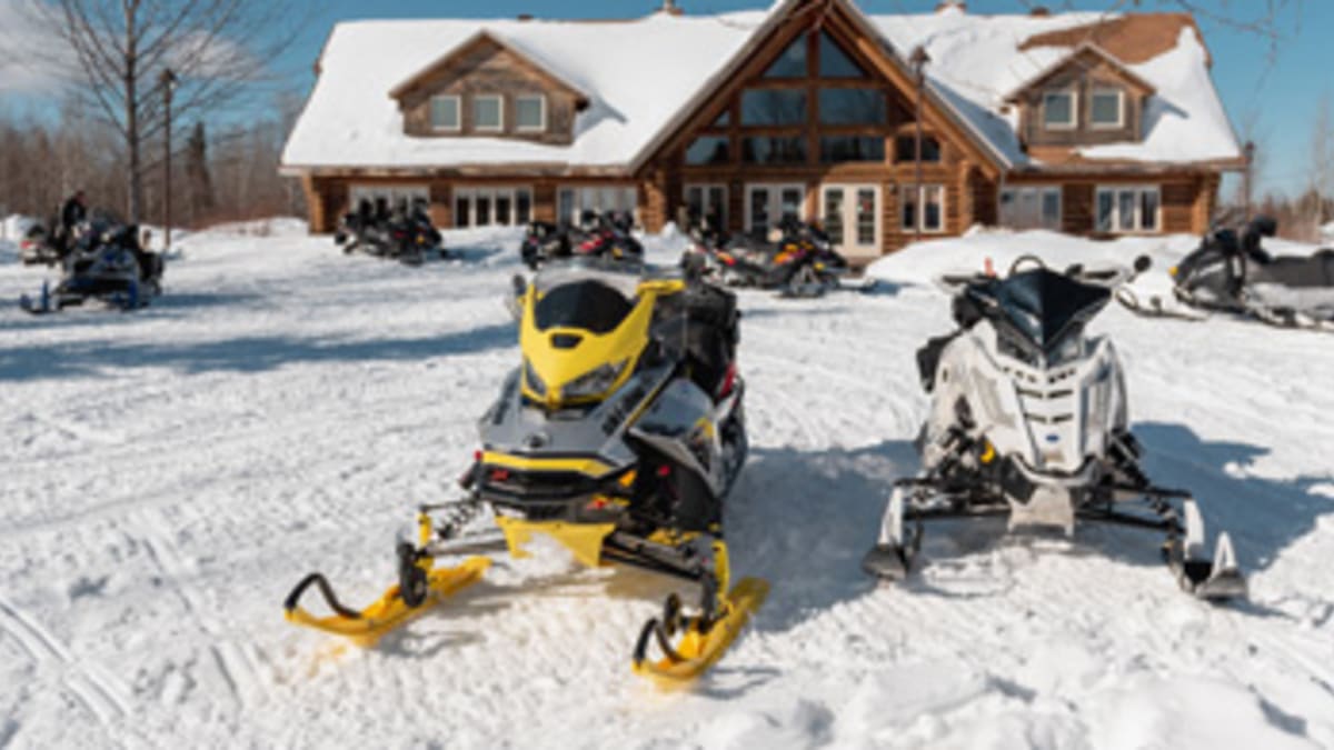 Two snowmobiles in front of a lodge