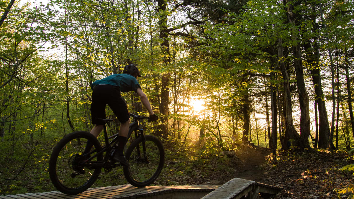 Cycliste en vélo de montagne dans le parc de la Gatineau en soirée.