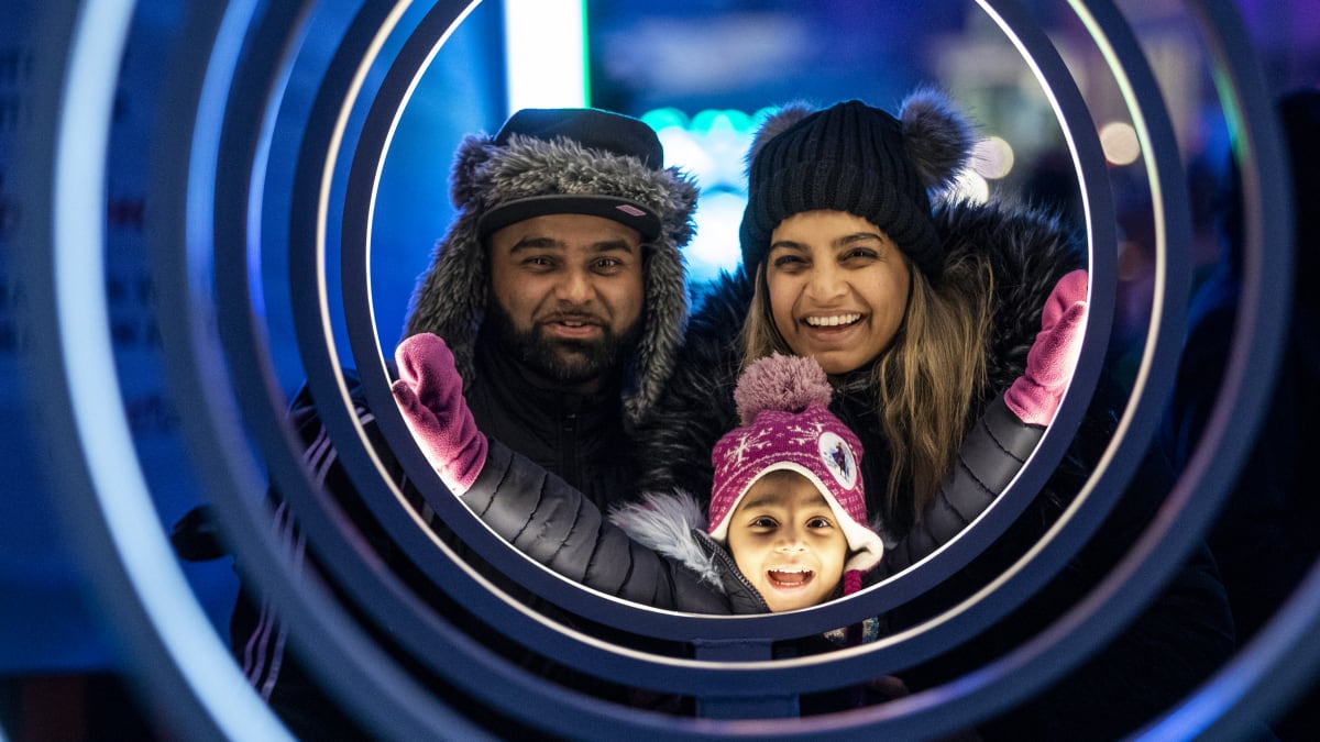 Smiling father, mother and little girl admiring a luminous installation at Winterlude.