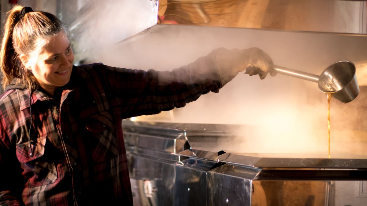 Woman preparing taffy on snow in a sugar shack.