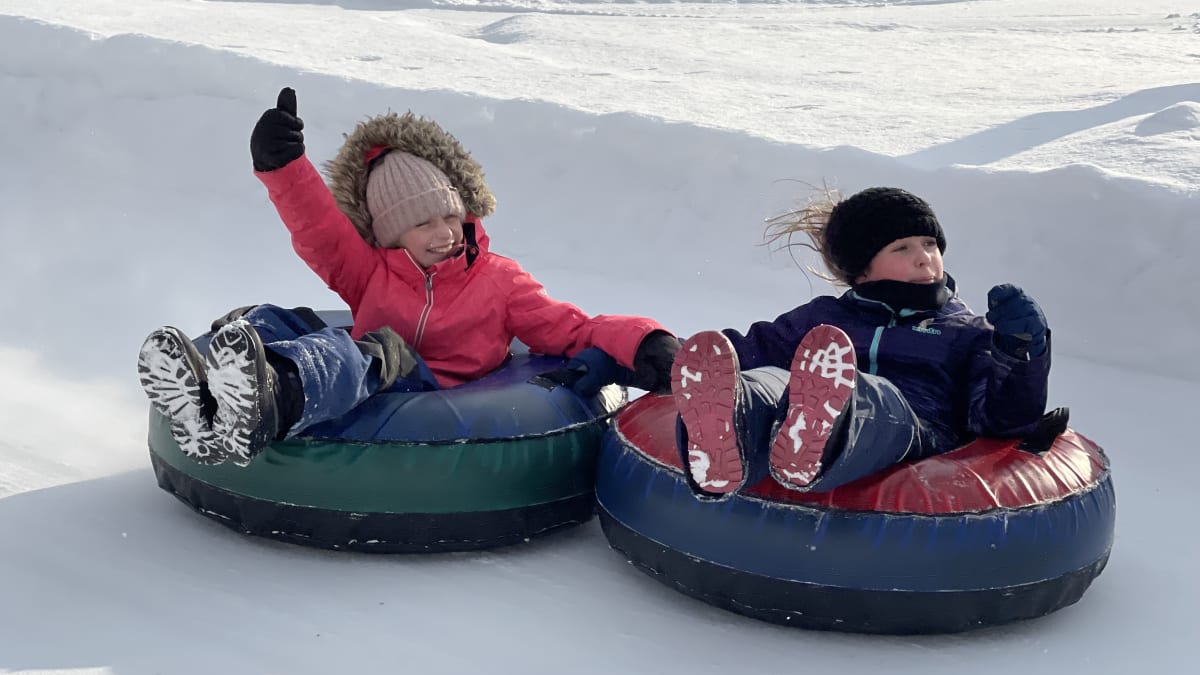 Two children sliding down on tubes.