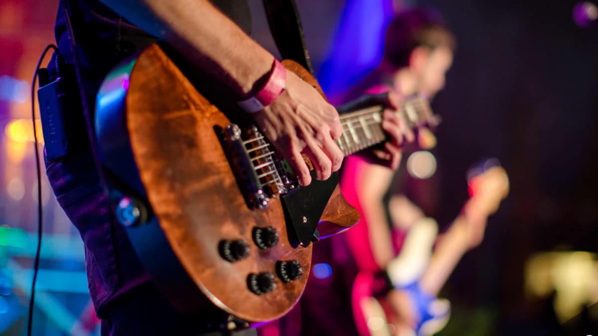 Musicien qui joue de la guitare en spectacle.