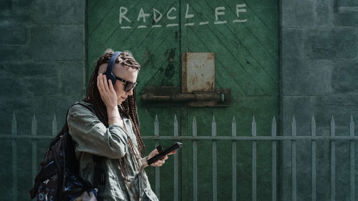 Young woman with an audio guide in front of a Radcliff sign