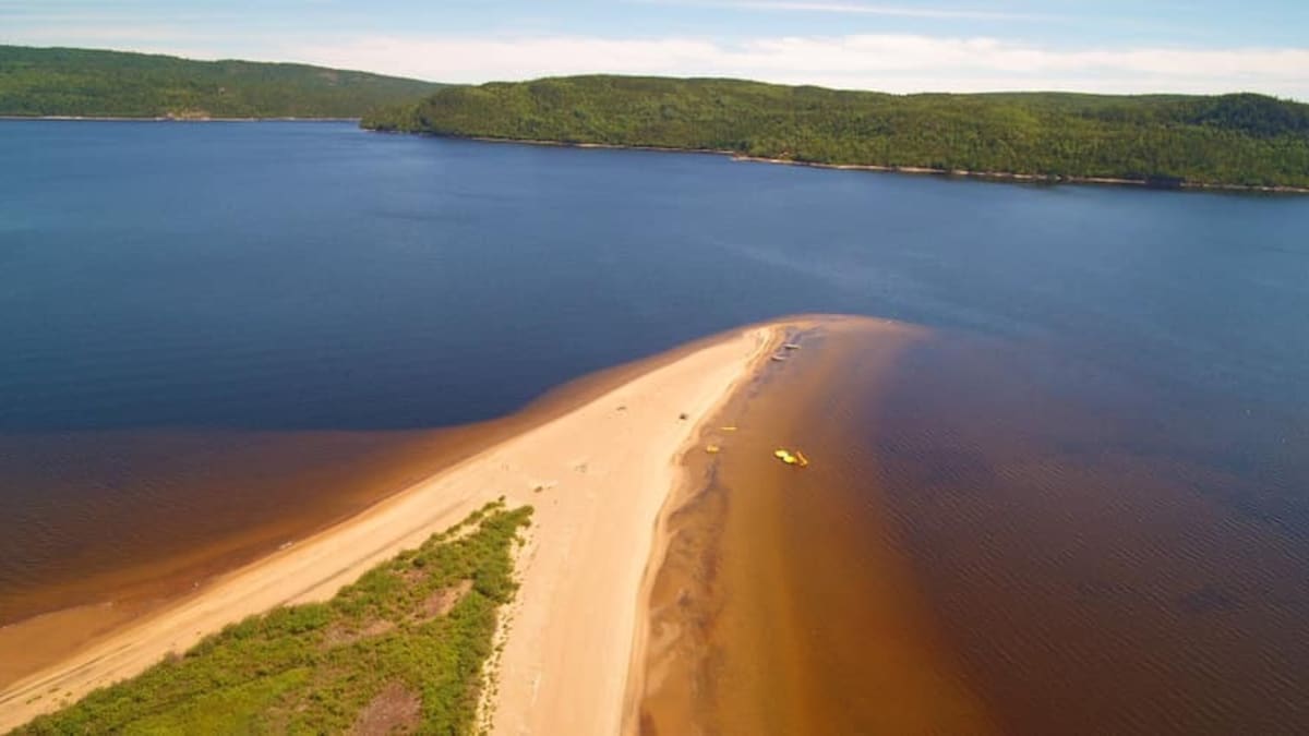 A sandy beach stretching into a lake.