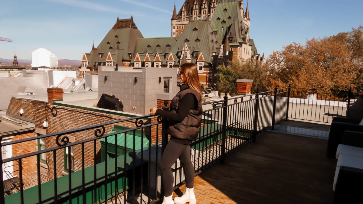A woman admiring the view of Québec City and the Château Frontenac from the rooftop terrace of the Hôtel-Manoir Vieux-Québec.