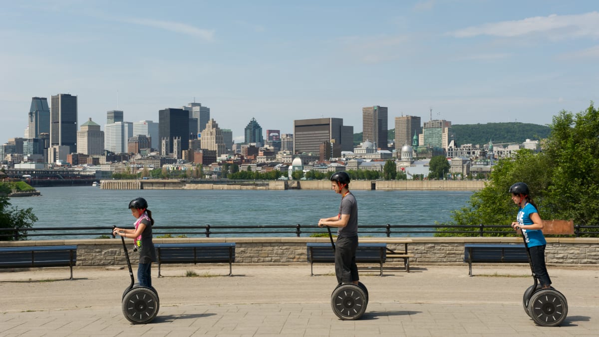 Trois personnes en Segway, avec Montréal en arrière-plan