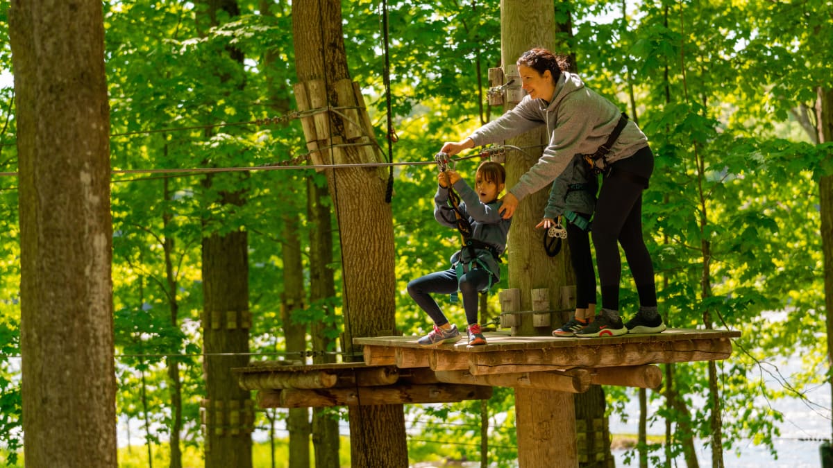 Mère et fille qui font un parcours dans les arbres à Extéria